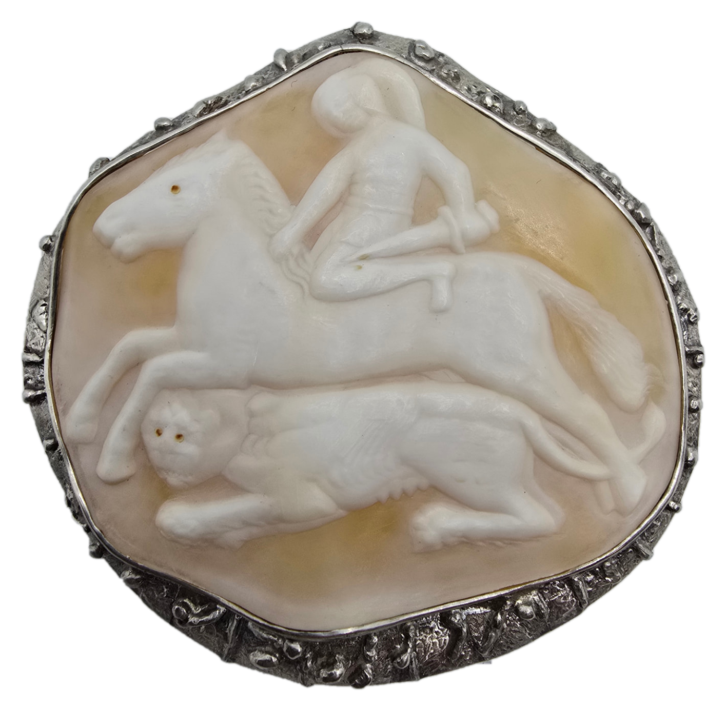 A hand-carved shell cameo of a rider and lion in a textured silver-tone setting